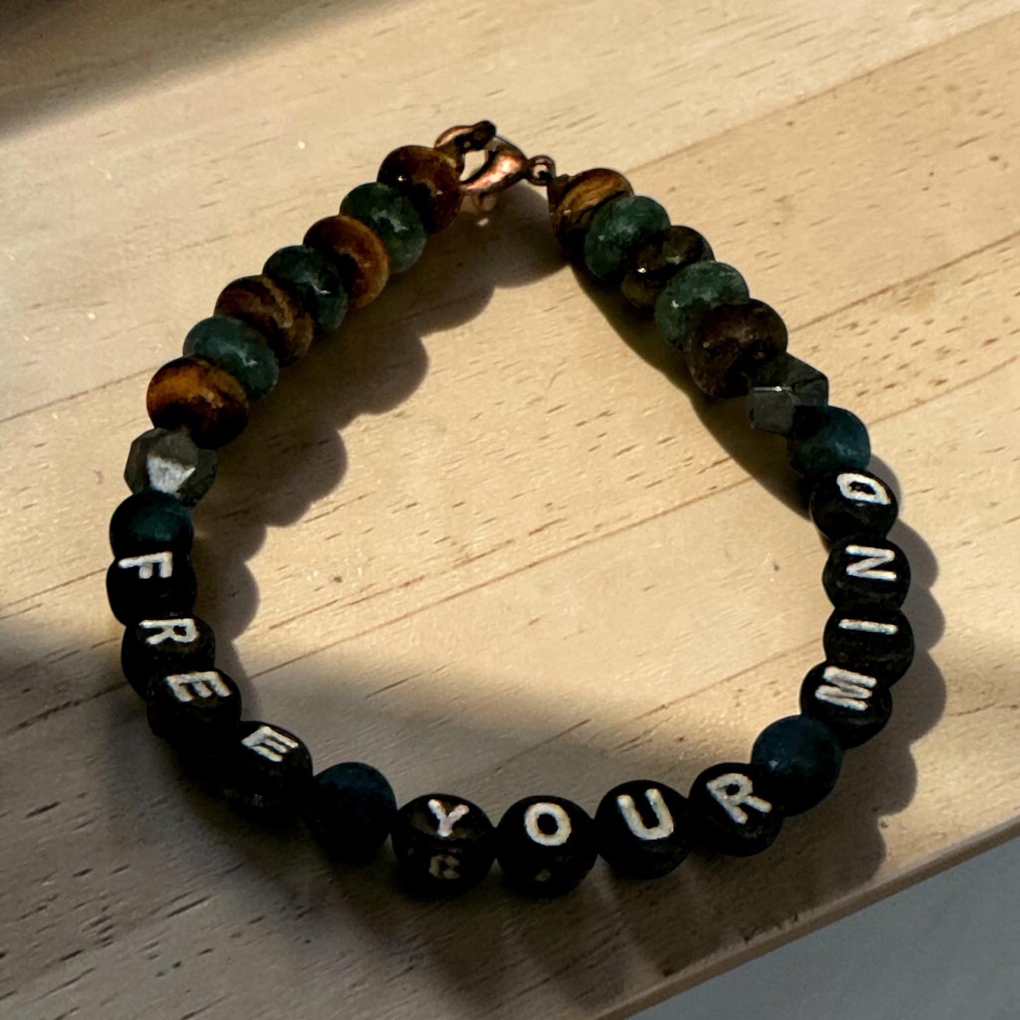 Bracelet with engraved message 'Free Your Mind' on a wooden surface
