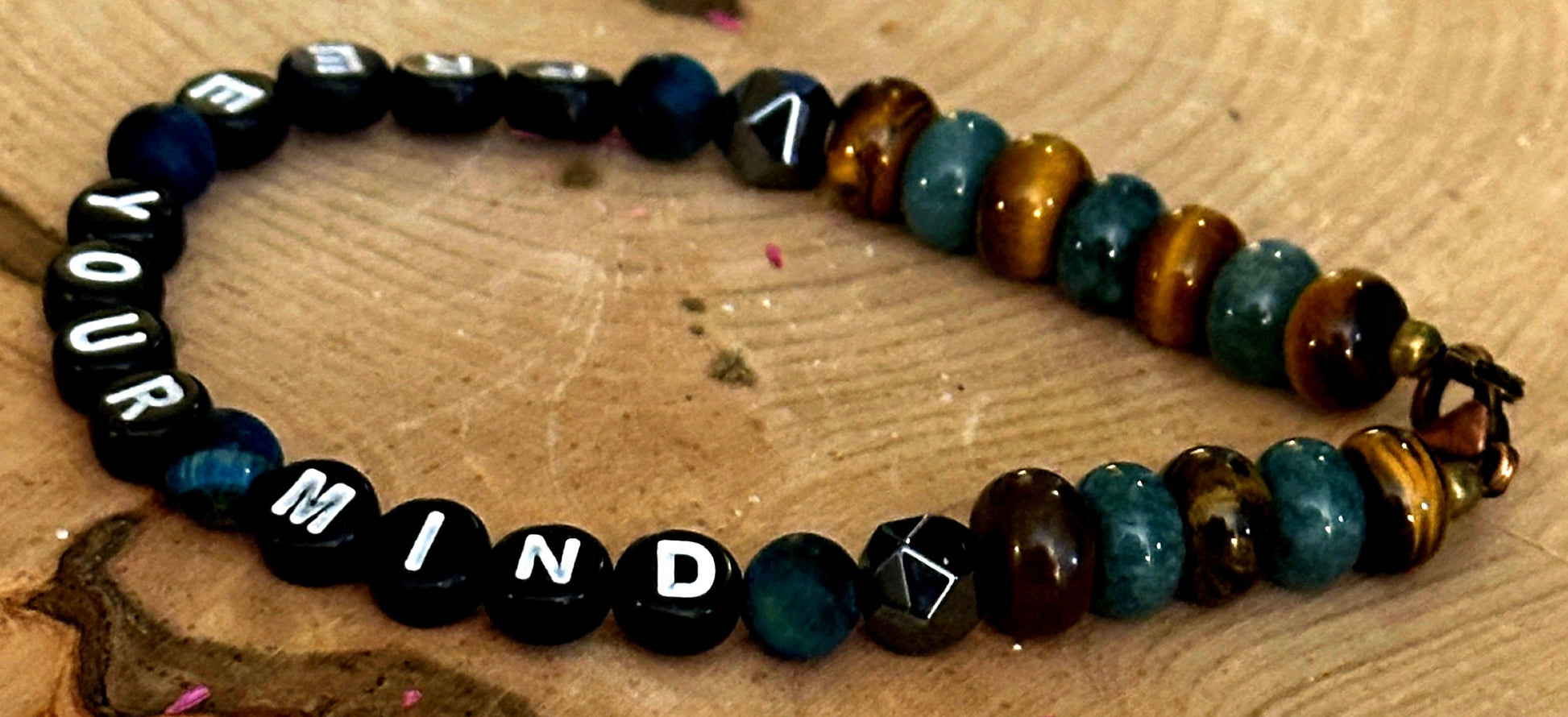 Tiger eye and teal gemstone bracelet displayed on natural wood surface