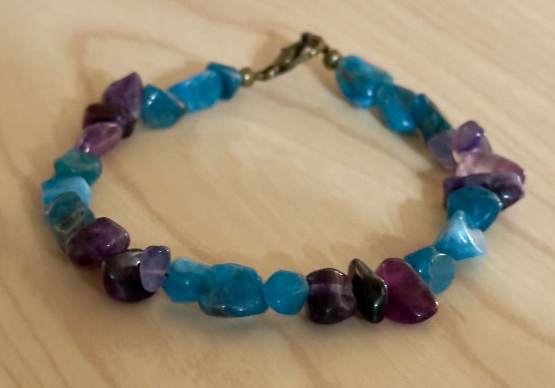     Blue Apatite and purple Amethyst chip bracelet displayed in circular shape on light wood surface