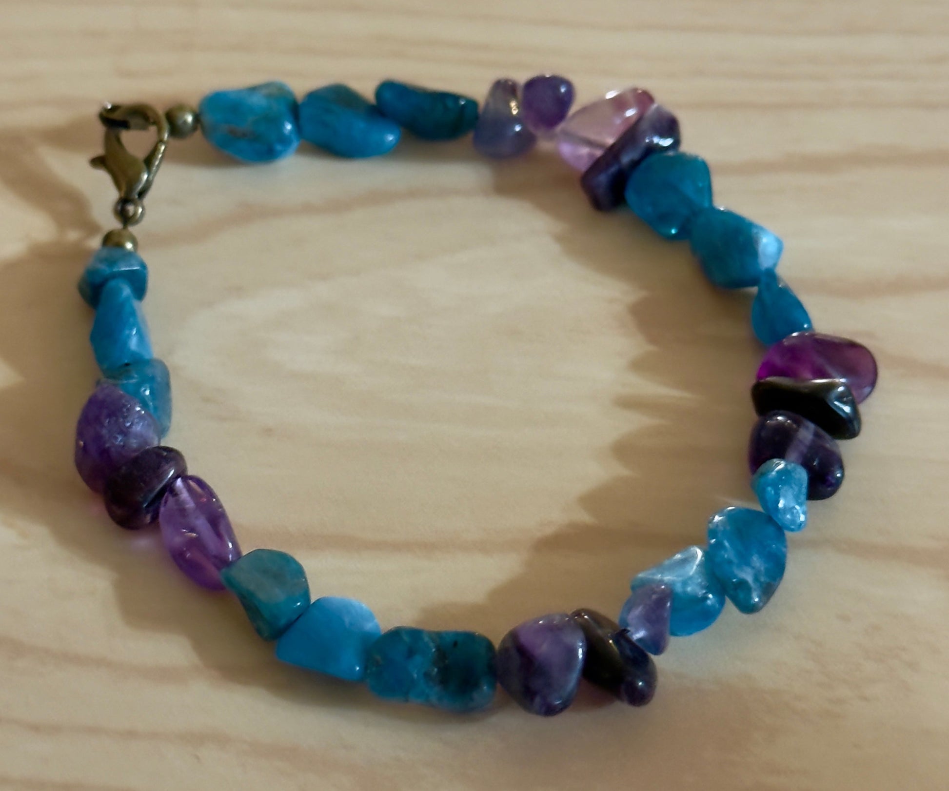     Handcrafted Apatite and Amethyst gemstone bracelet photographed on light wood background