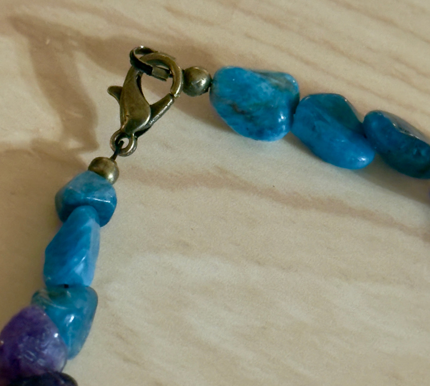     Close-up detail of brass lobster clasp and blue Apatite gemstone beads on handmade bracelet