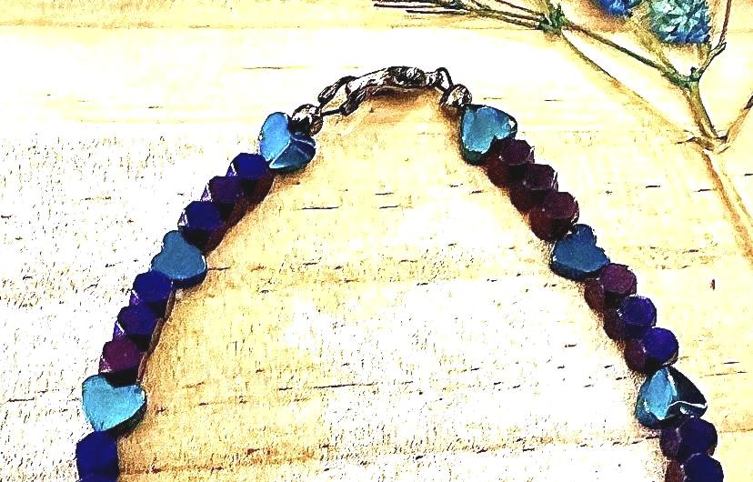 Full Heartspell Twilight bracelet arranged on a warm wood background, featuring rich purple and blue beads with turquoise heart accents.