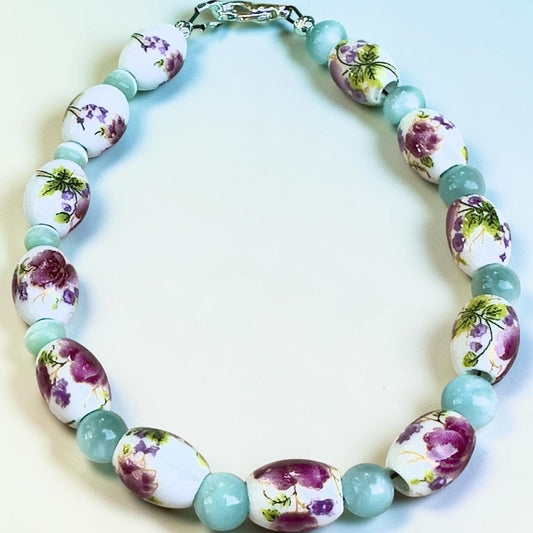 Hidden Reverie Meadow bracelet featuring floral porcelain beads with pink and purple wildflower designs and soft aqua accent beads.