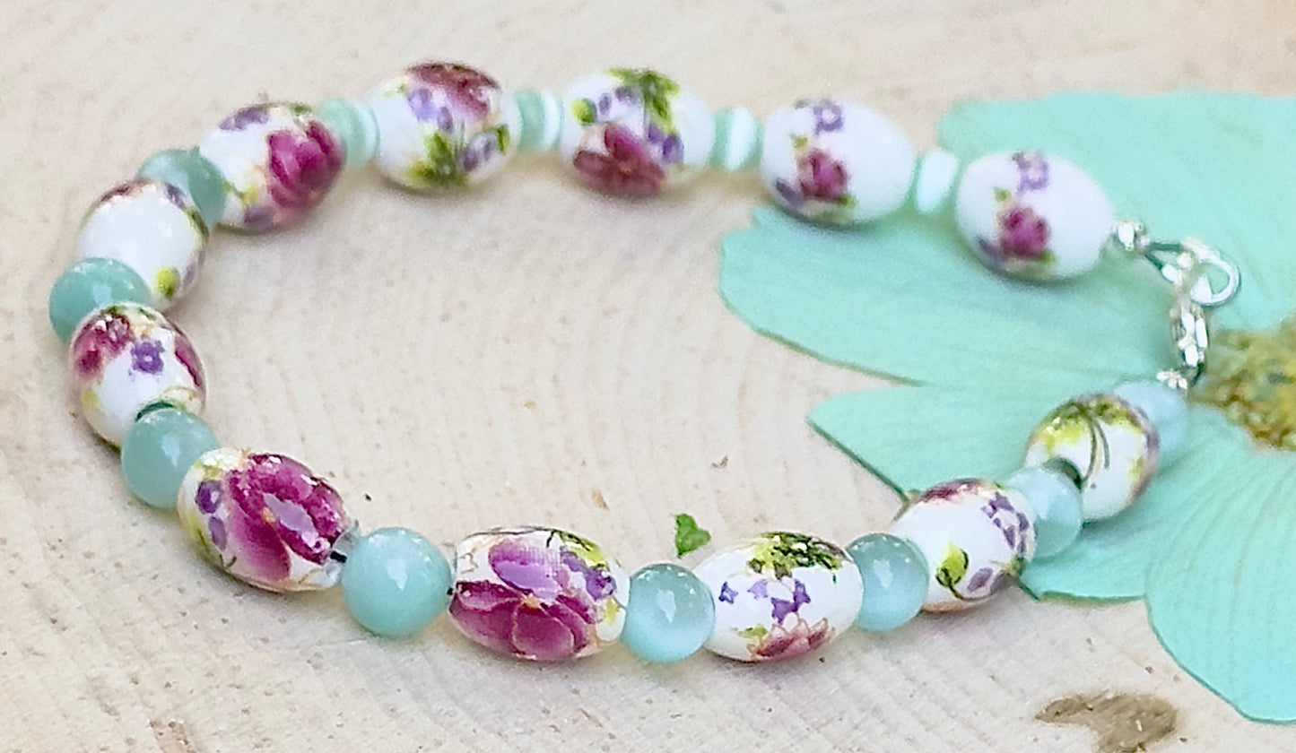 Handmade floral bracelet photographed at an angle showing porcelain wildflower beads and soft aqua accents.