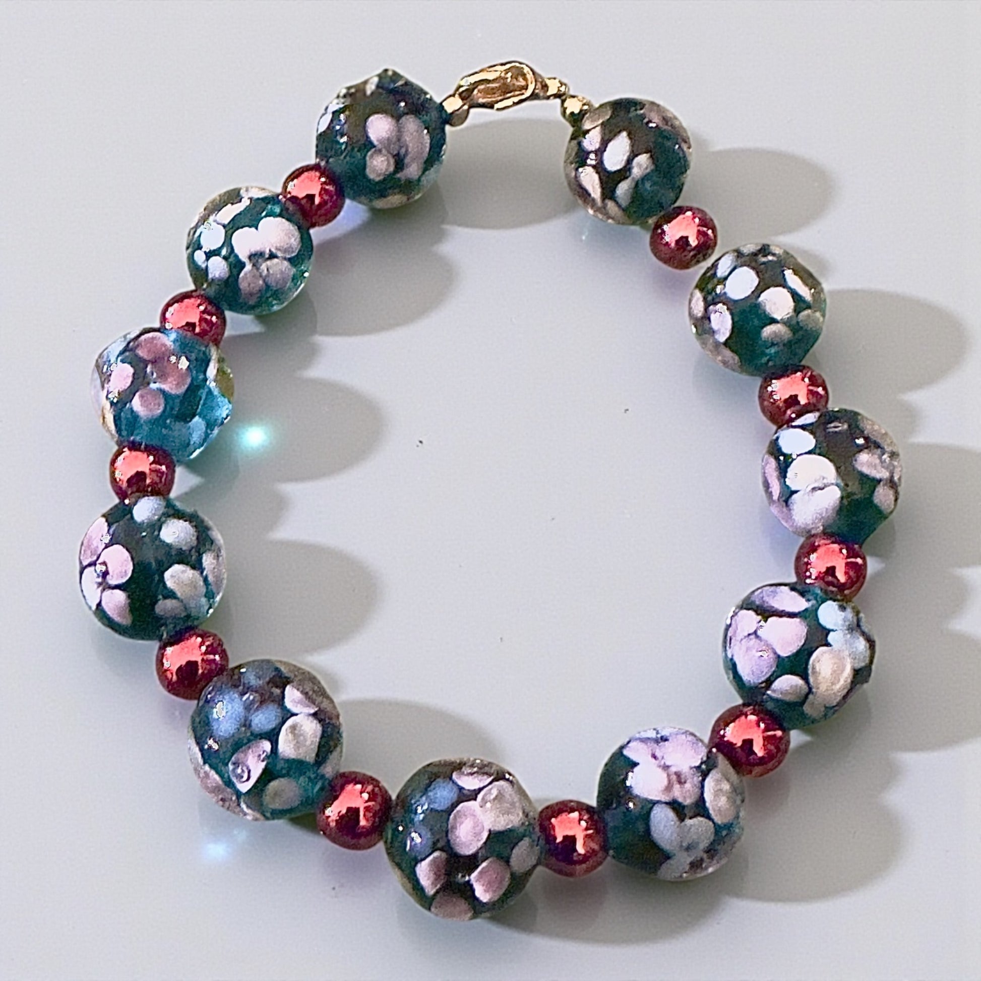 Handmade blue floral glass bead bracelet with copper spacers shown on a neutral background for detail view.
