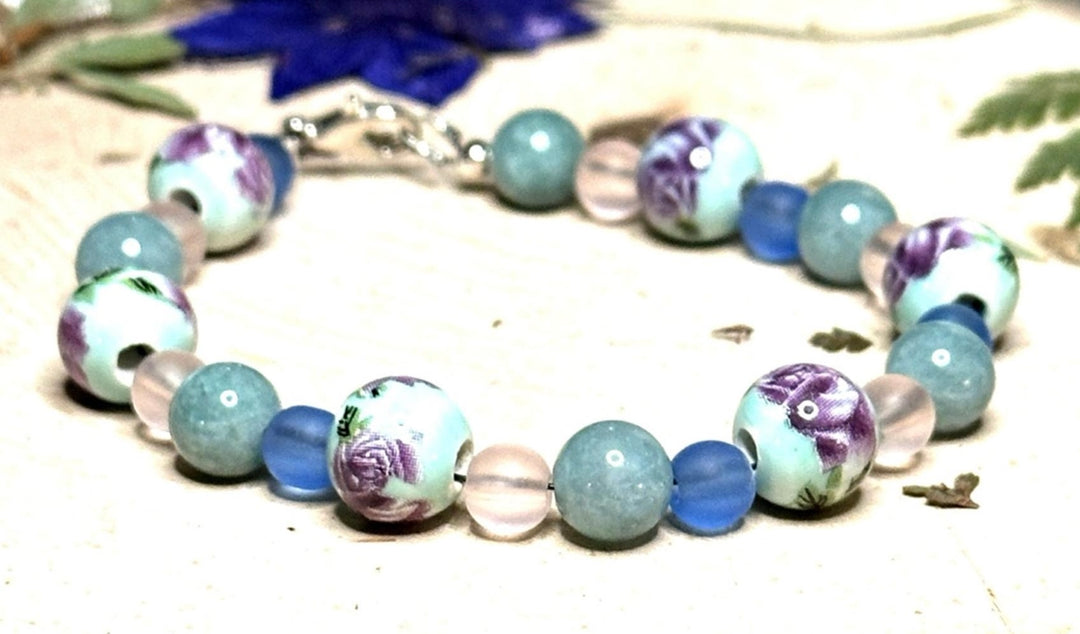 Close-up of handmade lavender and blue floral bracelet with artistic porcelain beads and ocean-inspired accents
