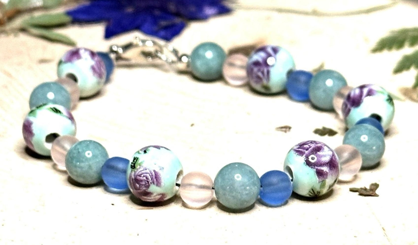 Close-up of handmade lavender and blue floral bracelet with artistic porcelain beads and ocean-inspired accents