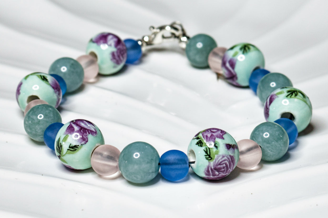 Floral ocean-inspired beaded bracelet displayed on white dish with calming lavender and blue tones