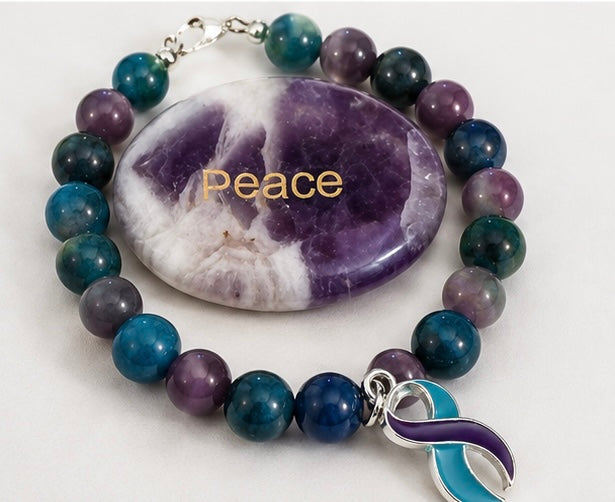 Blue, teal and purple gemstone awareness bracelet displayed with a polished amethyst Peace stone