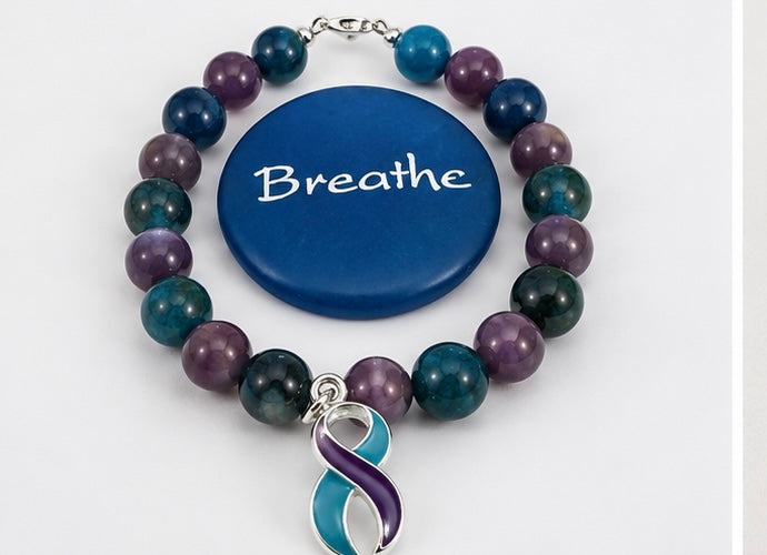 Gemstone awareness bracelet displayed beside a blue Breathe meditation stone.
