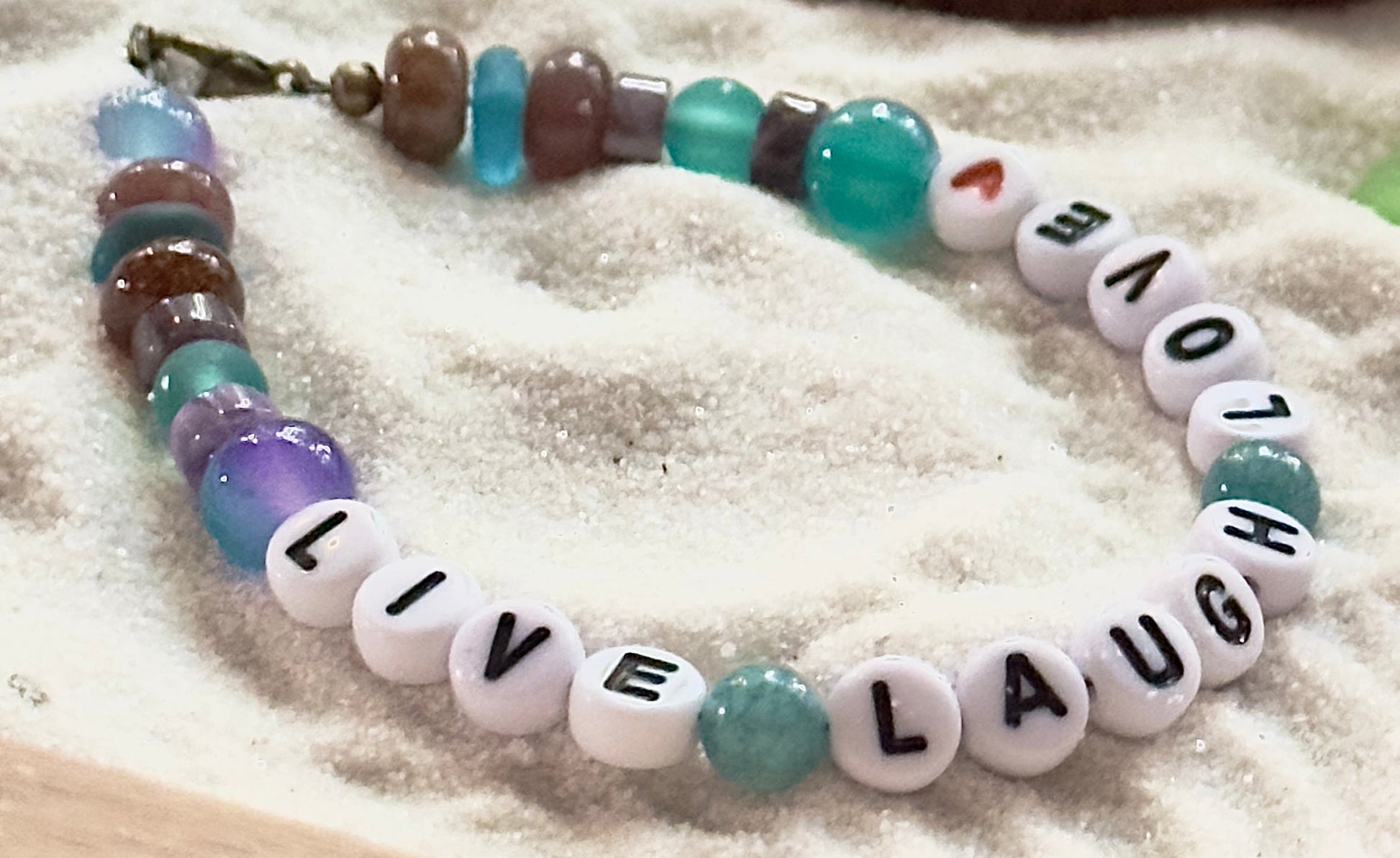 close up of gemstone beads in teal brown and lavender tones with letter beads spelling love laugh live