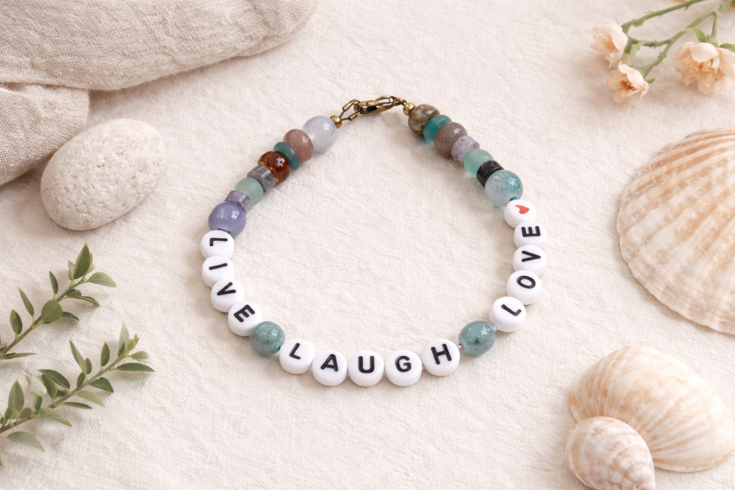 Beaded bracelet with 'Live Laugh Love' on a natural setting with stones and flowers