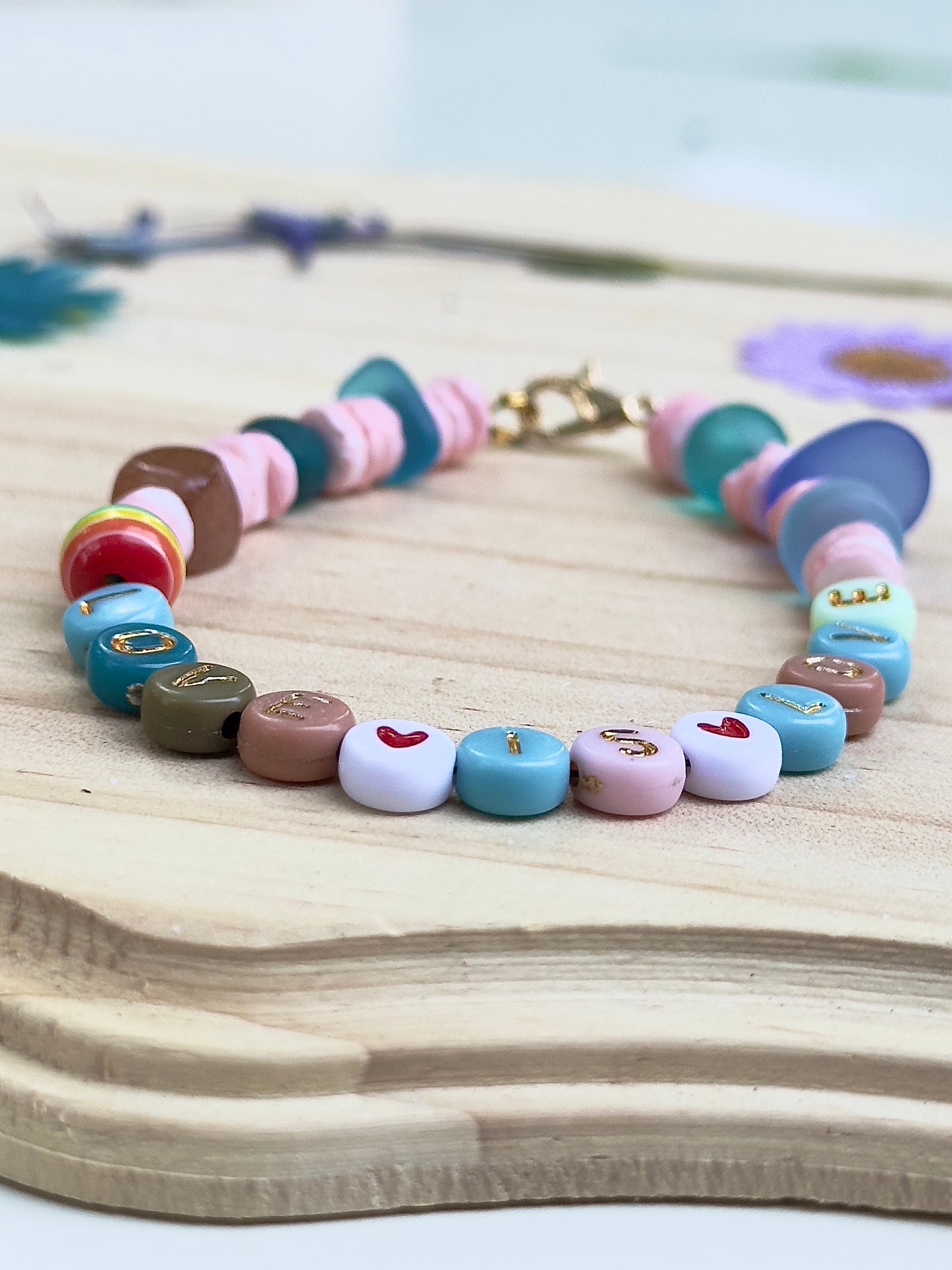 Close-up of the “LOVE IS LOVE” letter beads and heart details on a handmade pastel beaded bracelet.