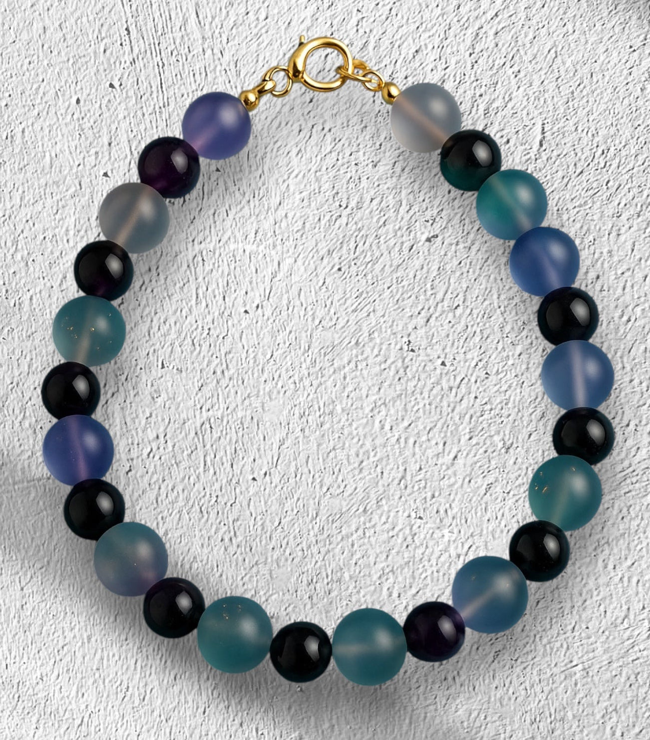 Lunar Twilight Galaxy handmade gemstone bracelet with frosted blue, teal, purple, gray, and black beads displayed on a white textured background.