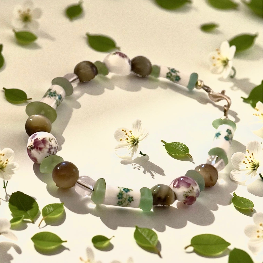 Meadowlight bracelet styled among soft green leaves and delicate white flowers.