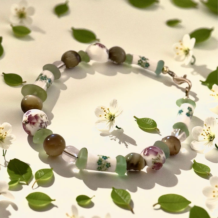 Meadowlight bracelet styled among soft green leaves and delicate white flowers.