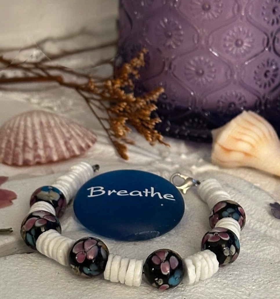 Moonlit Garden bracelet with a blue “Breathe” stone, seashells, dried stems, and a purple candle.