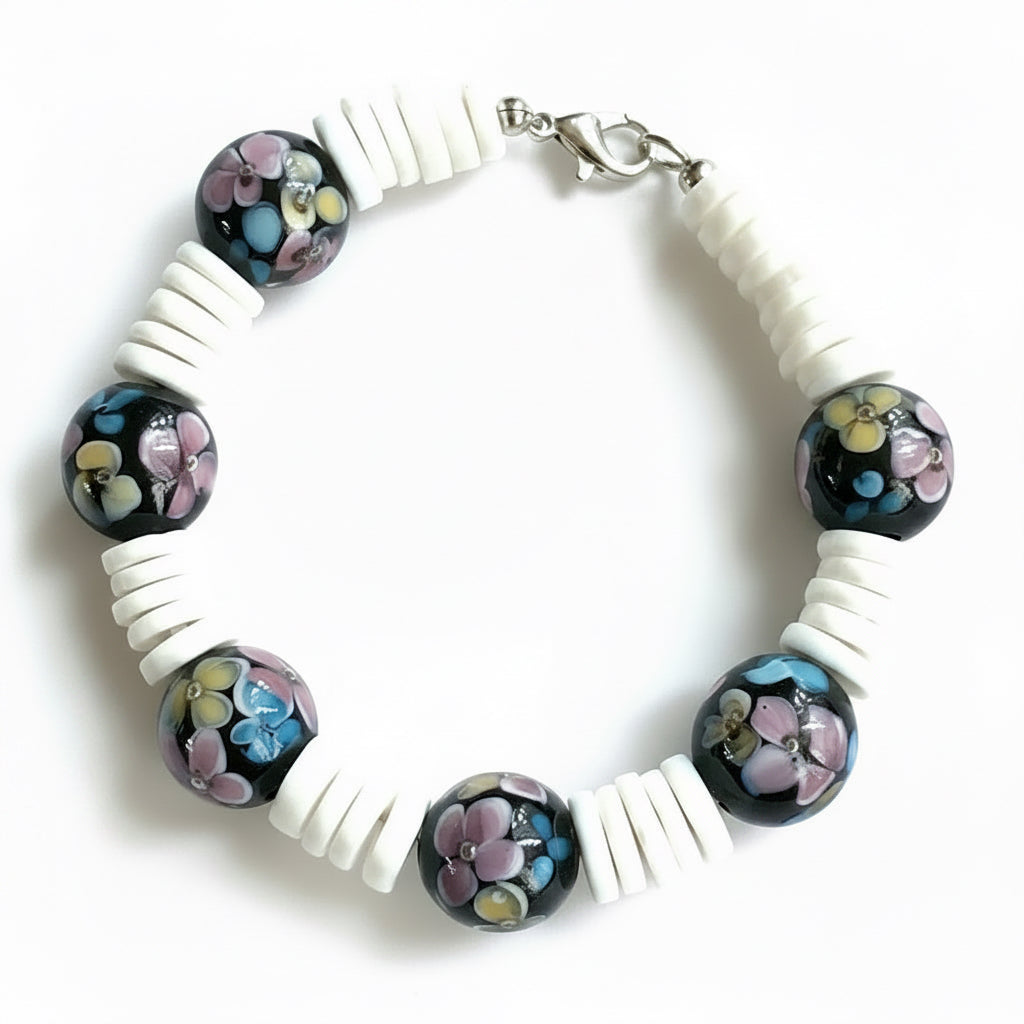 Moonlit Garden bracelet with black floral beads, white disc beads, and a silver-tone lobster clasp on a white background.