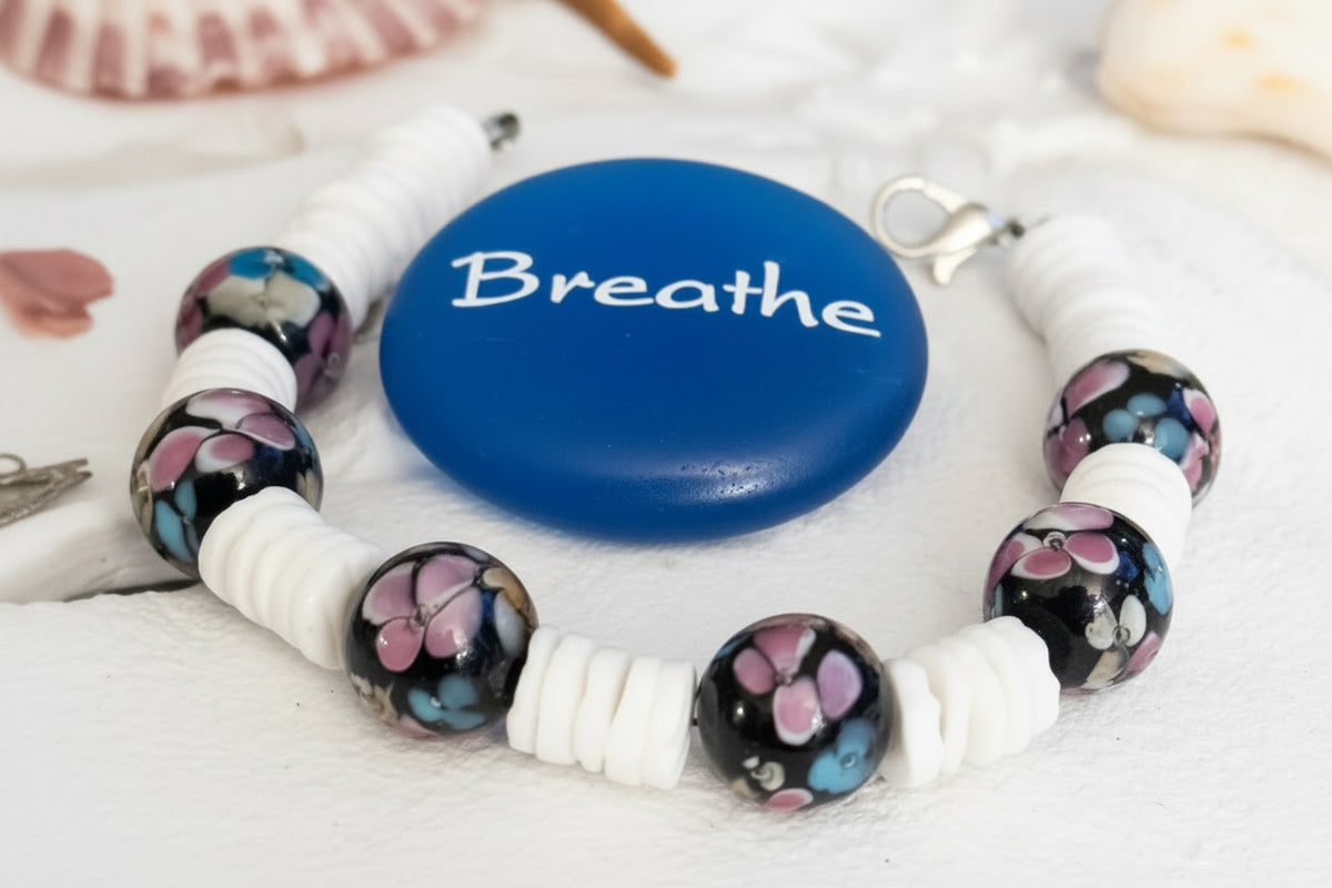 Close view of Moonlit Garden’s pink and blue floral beads and white spacers beside a blue “Breathe” stone.