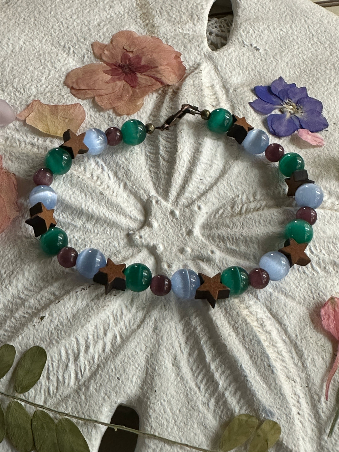 Cat's eye moon and star bracelet styled with flowers and natural textures for calming and grounding aesthetic