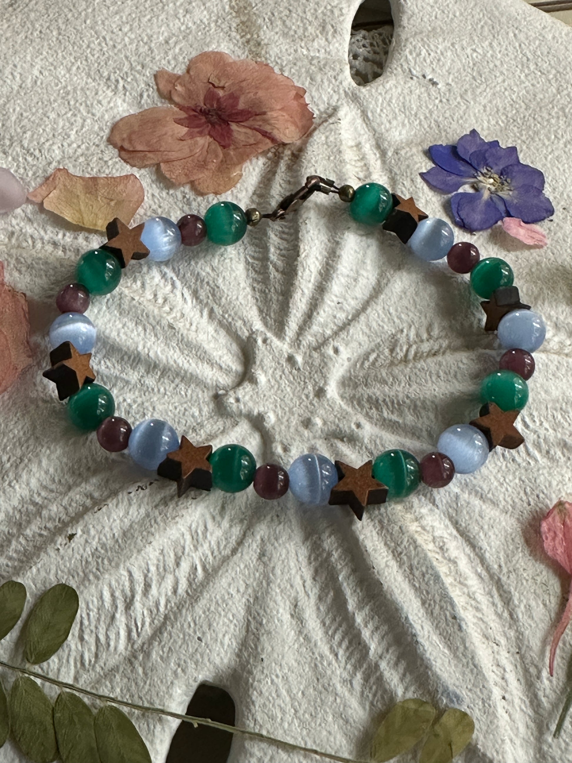 Cat's eye moon and star bracelet styled with flowers and natural textures for calming and grounding aesthetic