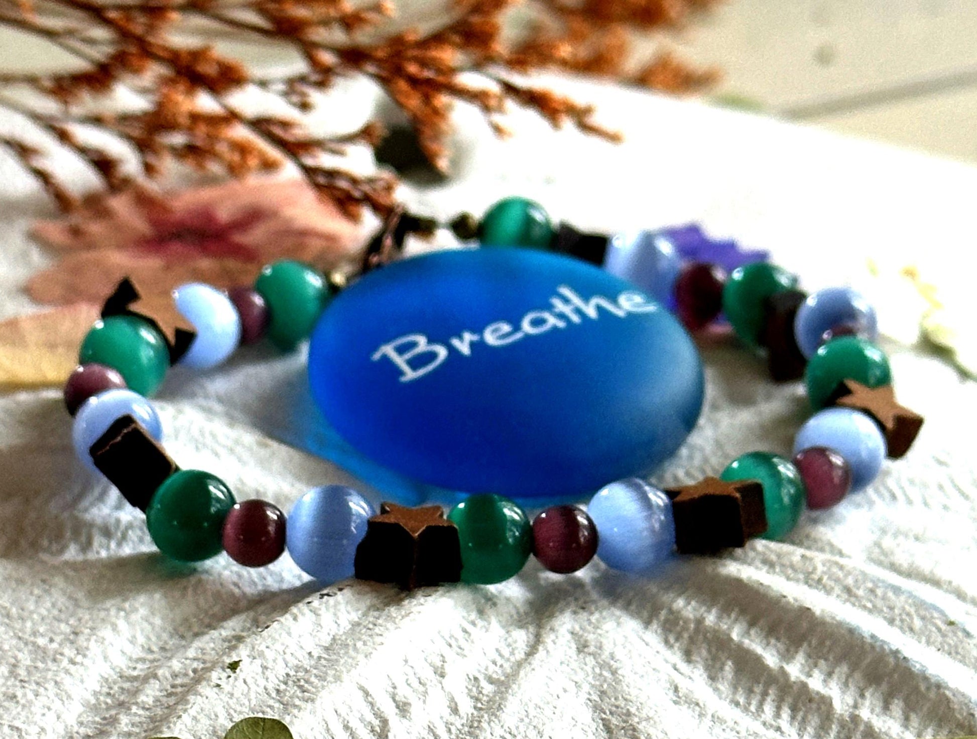 Close up of cat's eye beads showing shimmer in blue green and purple tones on handmade bracelet