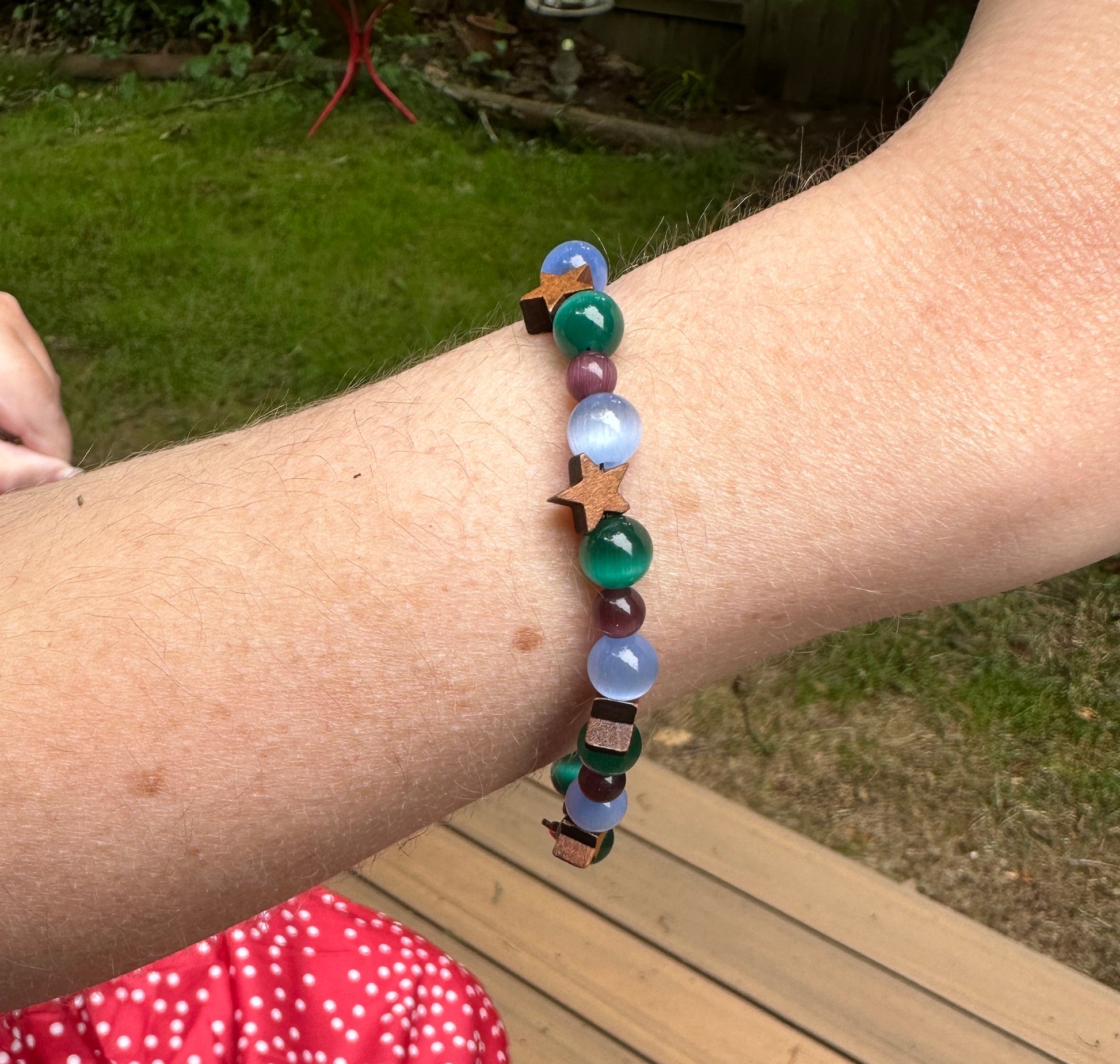 Woman wearing cat's eye gemstone bracelet with moon and star design for calm and grounding energy