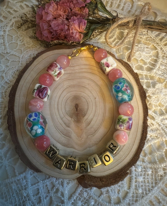 Breast cancer awareness bracelet featuring colorful beads and the word 'WARRIOR' to symbolize strength and support.