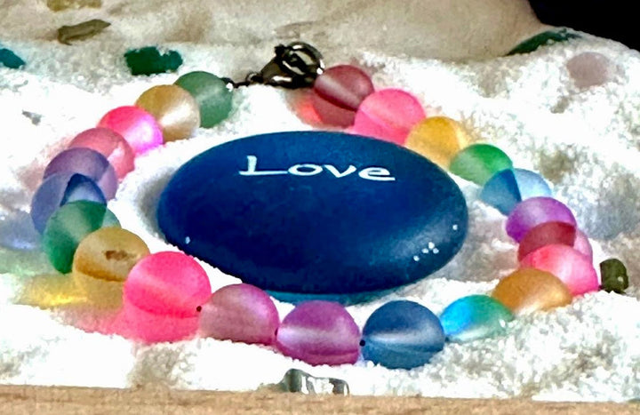 Rainbow Pride bracelet arranged around a blue Love stone symbolizing love, belonging, and self-expression.