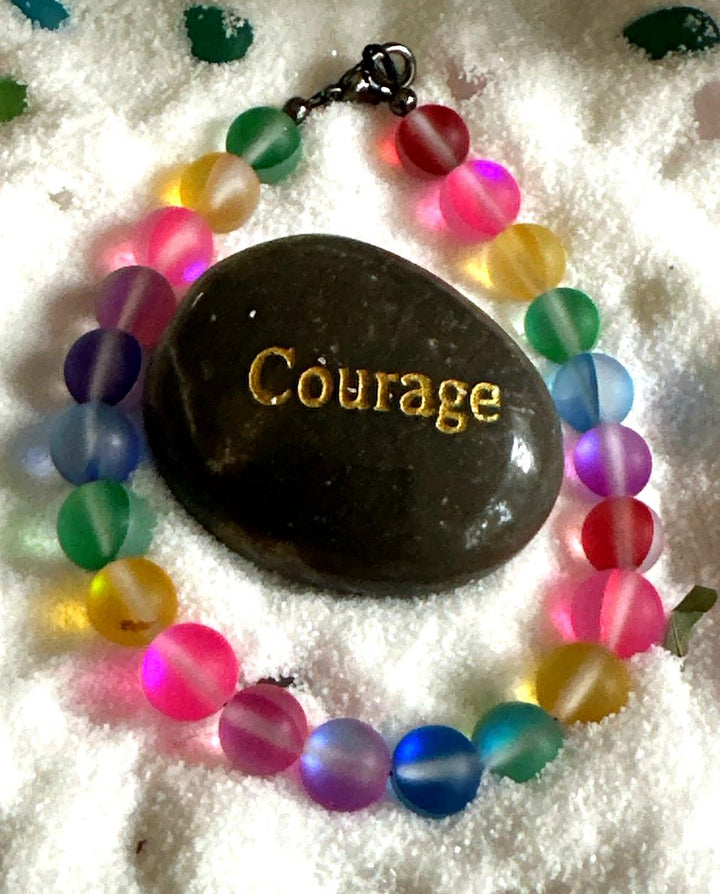 Rainbow bracelet displayed around a Courage stone celebrating authenticity, strength, and Pride Month.