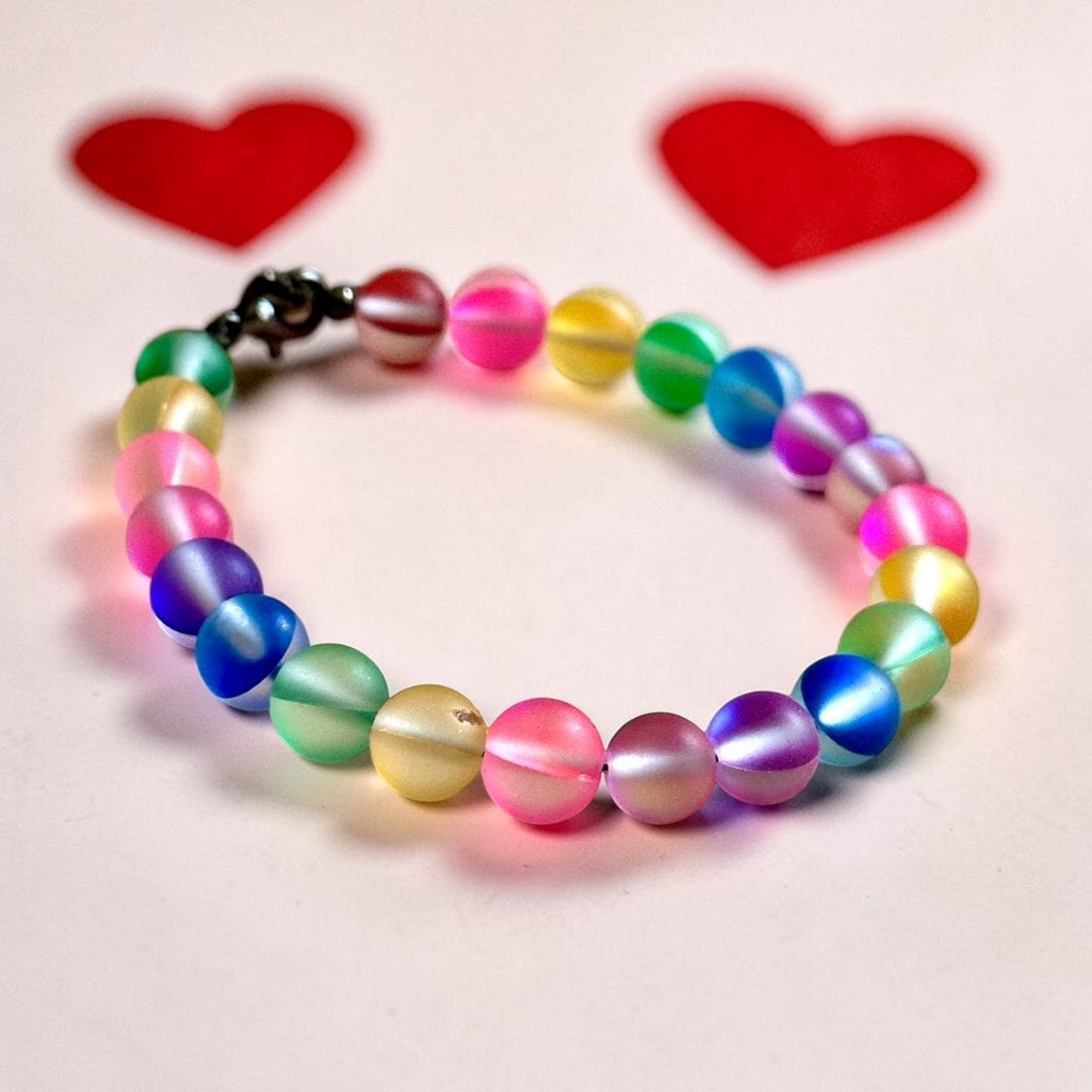 Handmade rainbow bracelet photographed on natural wood showing colorful frosted glass beads and lobster clasp closure.