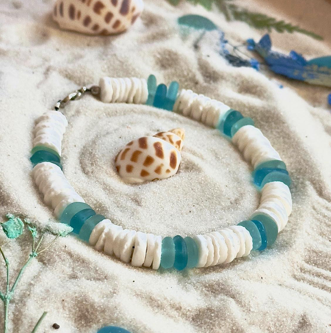 Ocean inspired beach bracelet displayed in soft sand with seashell accents and coastal styling
