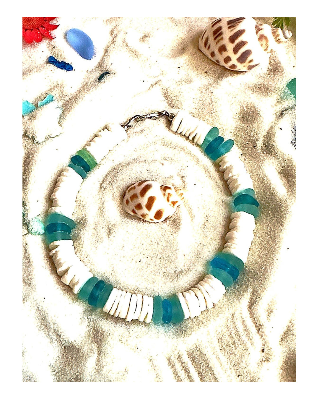 Seafoam and shell bracelet styled with seashell centerpiece in coastal flat lay setting