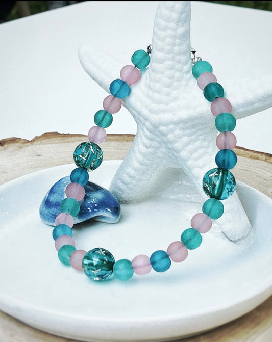 Colorful beaded bracelet on a starfish and shell with a white background