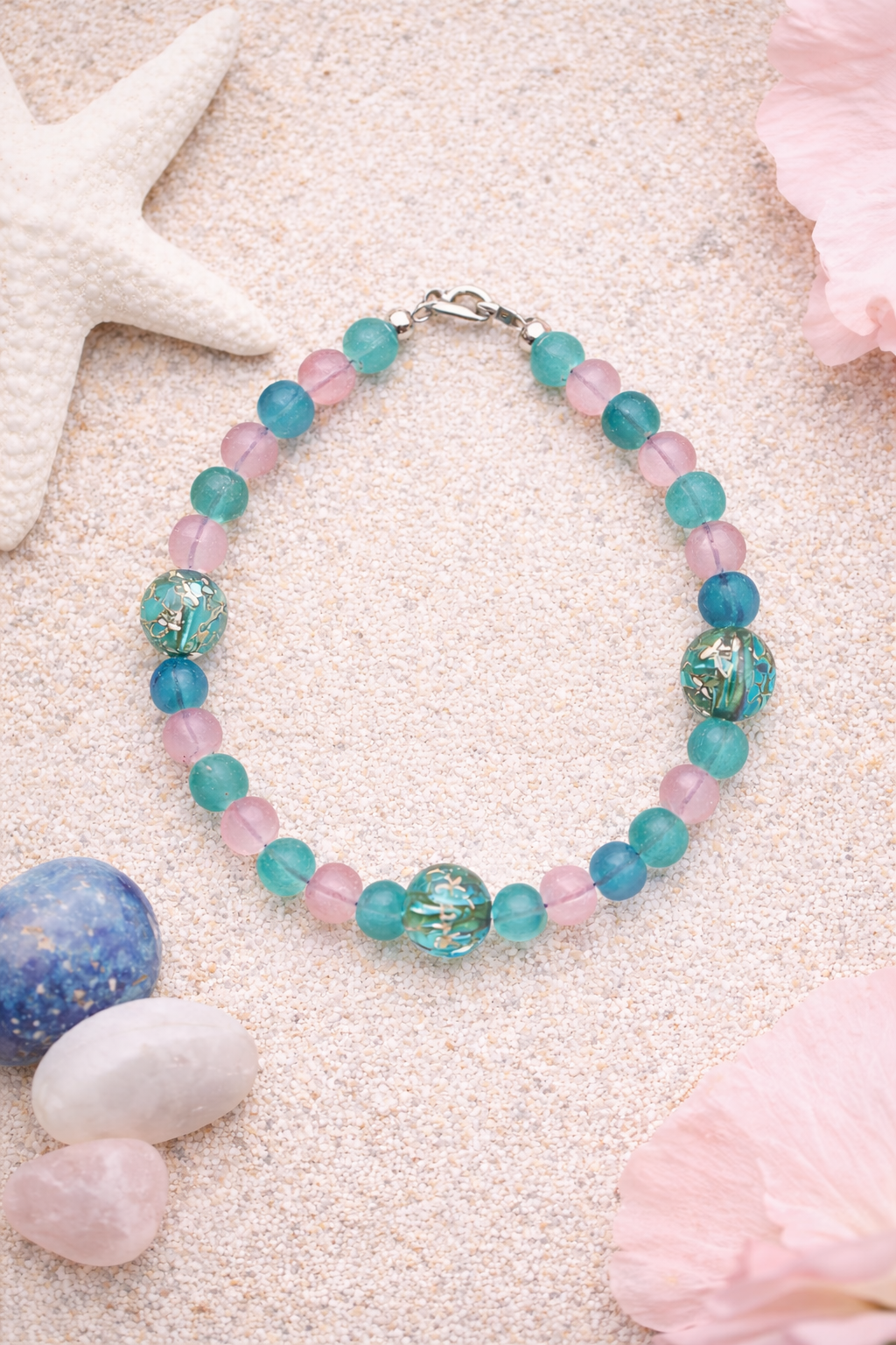 coastal gemstone bracelet with seafoam green and blush beads on sand with shells beach inspired handmade jewelry