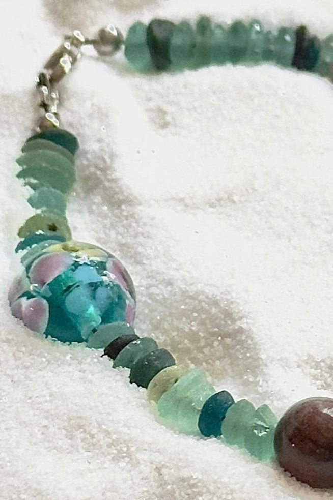 Close-up of hand-painted floral bead in pink and purple on handmade bracelet