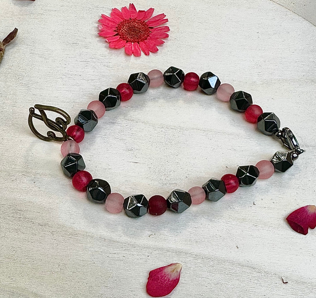 Angled view of the Soul Connection handmade bracelet featuring polished pink and raspberry beads with metallic hematite accents.