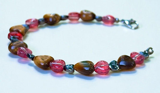 Handmade pink and earthy gemstone bracelet with glass bead accents on neutral background