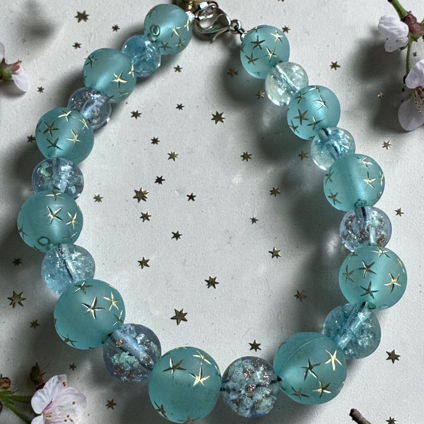 Starfall Constellations bracelet arranged on a white background with scattered stars, emphasizing its celestial theme.