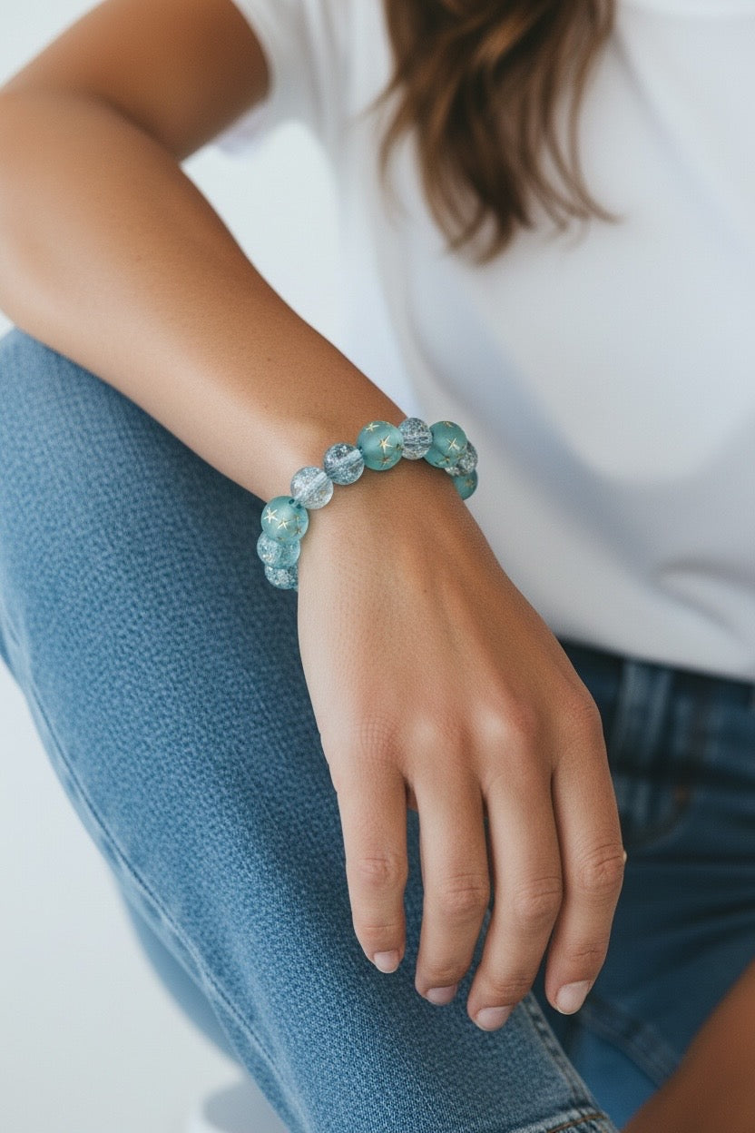 Model wearing the Starfall Constellations bracelet featuring aqua-blue celestial beads with gold stars and crystal accents.