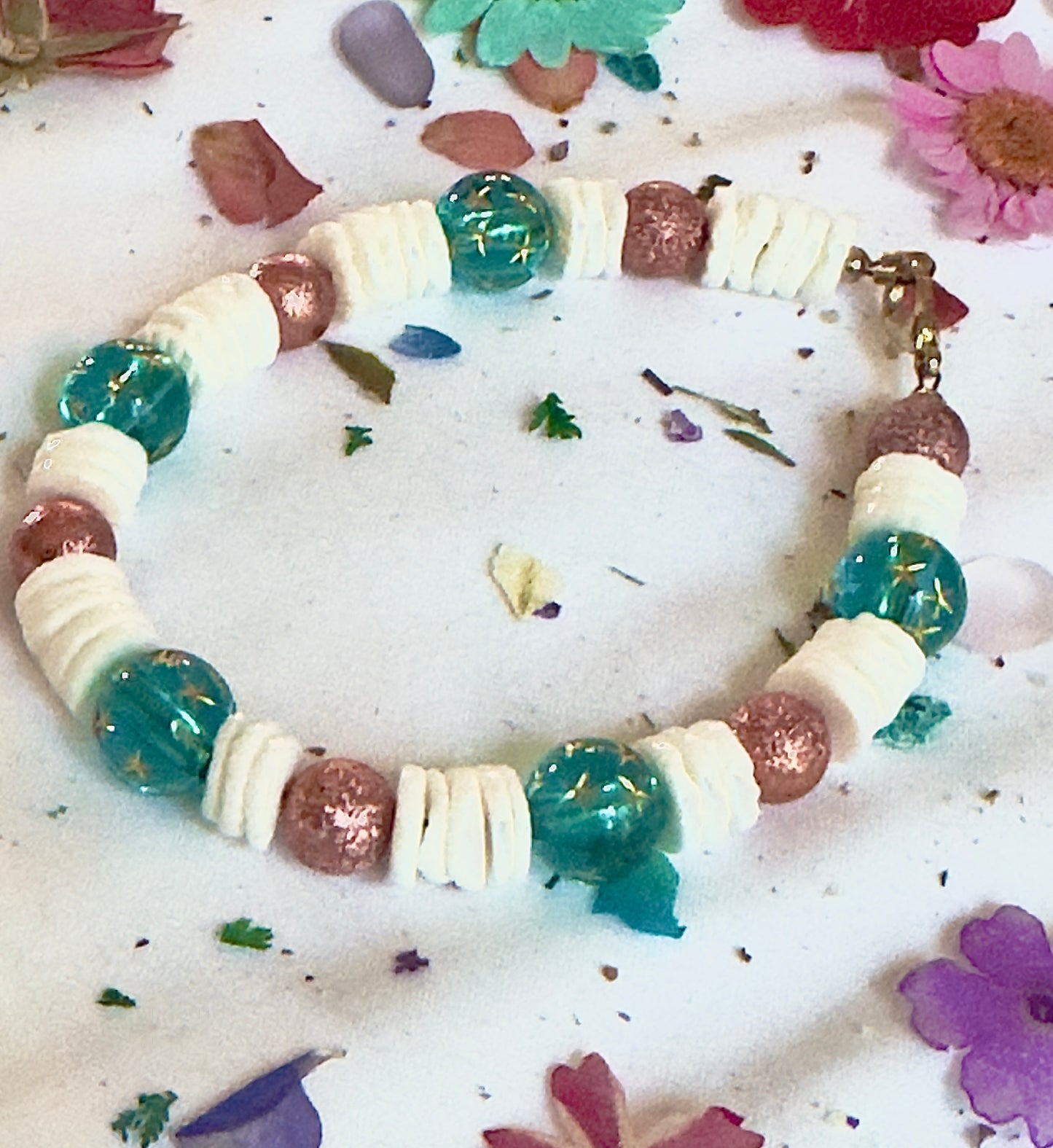Coastal cosmic bracelet displayed in soft beach-inspired flat lay styling