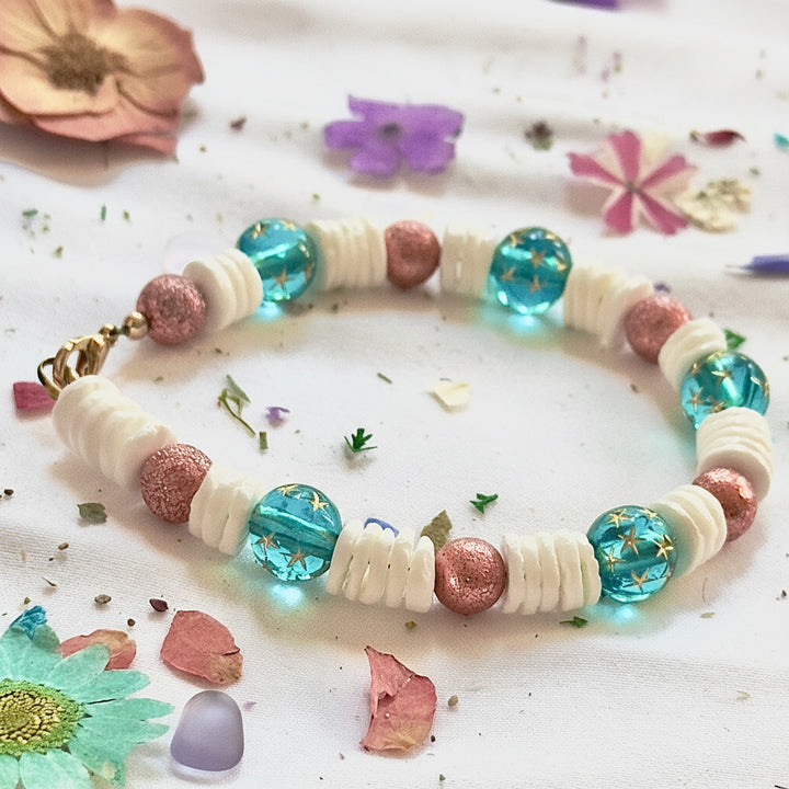 Handmade whimsical bracelet with teal galaxy beads, pink shimmer accents, and coastal-inspired details