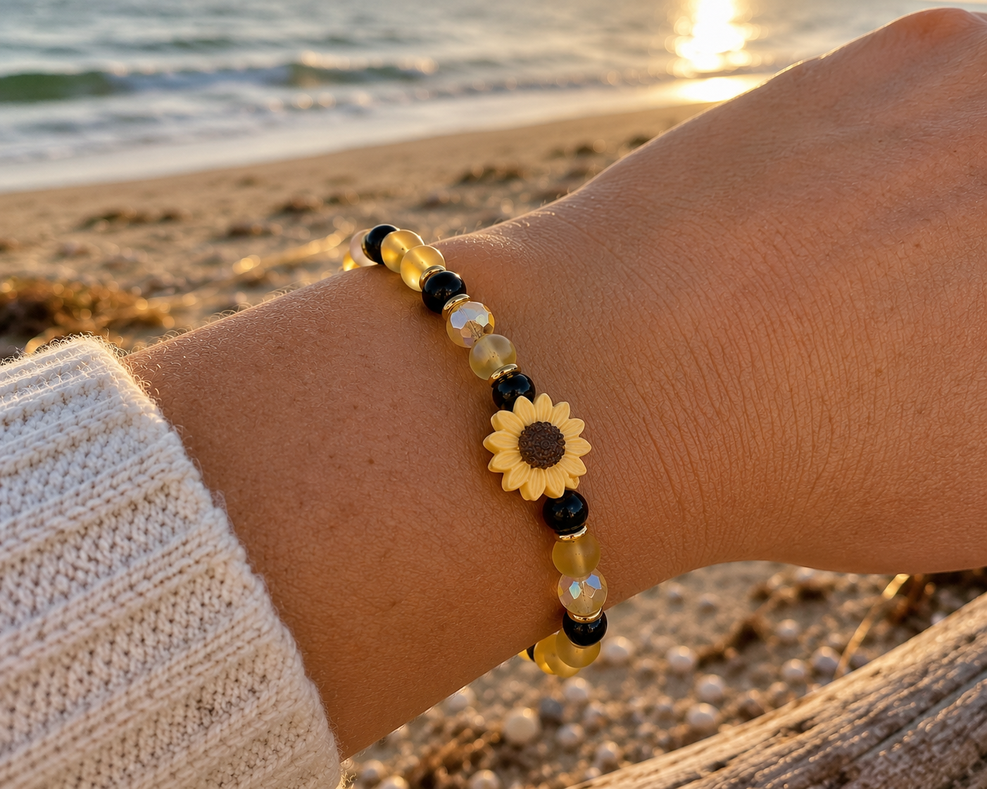 Sunflower Anchor bracelet worn on a wrist at sunset by the beach, featuring frosted yellow beads, black accents, and a handmade clay sunflower focal bead.