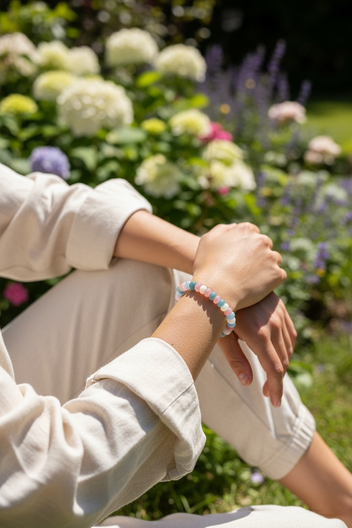 Handmade Trans Pride bracelet worn on a wrist featuring soft pink, blue, and white beads symbolizing authenticity, self-expression, and pride.