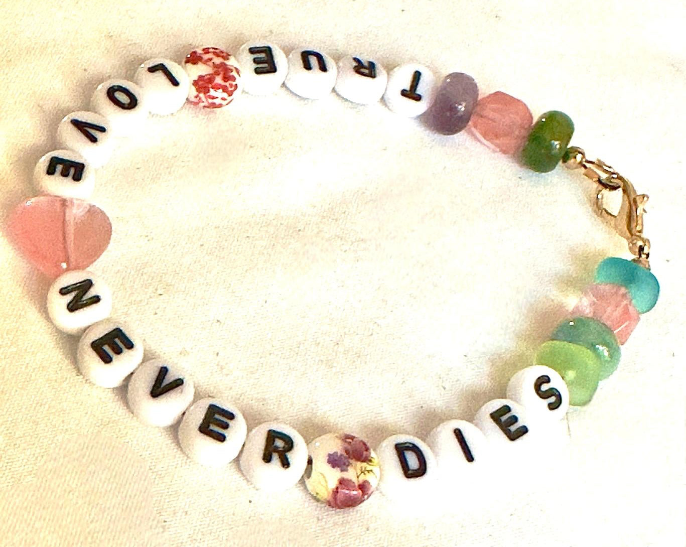 Flat lay of the True Love Never Dies bracelet arranged in a circle, showing the full message and colorful bead arrangement.
