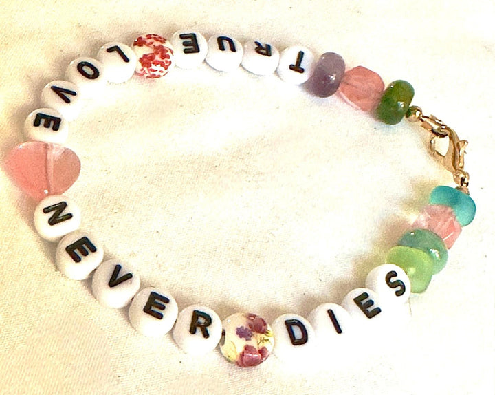 Flat lay of the True Love Never Dies bracelet arranged in a circle, showing the full message and colorful bead arrangement.