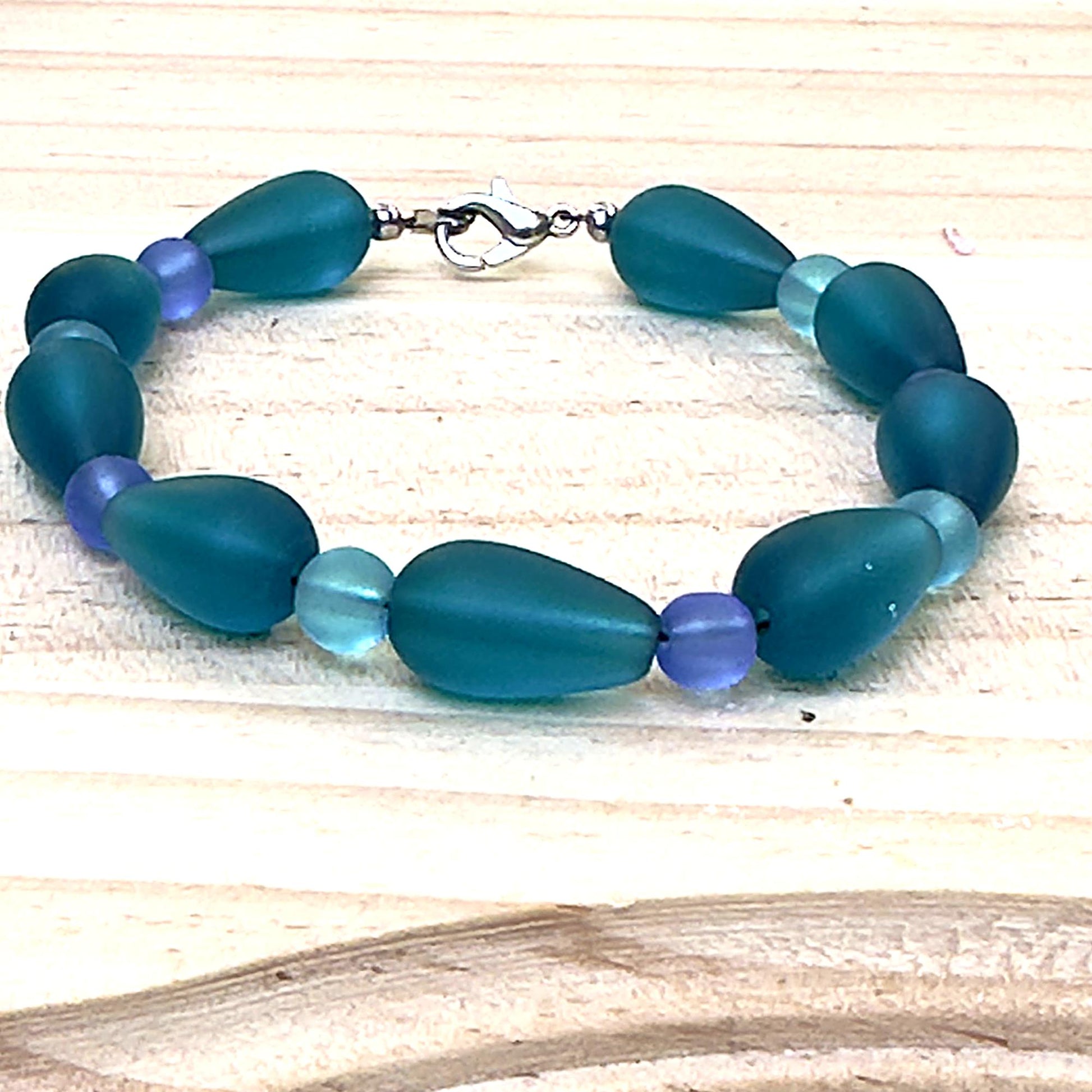 Handmade teal gemstone style bracelet photographed on white textured coastal backdrop