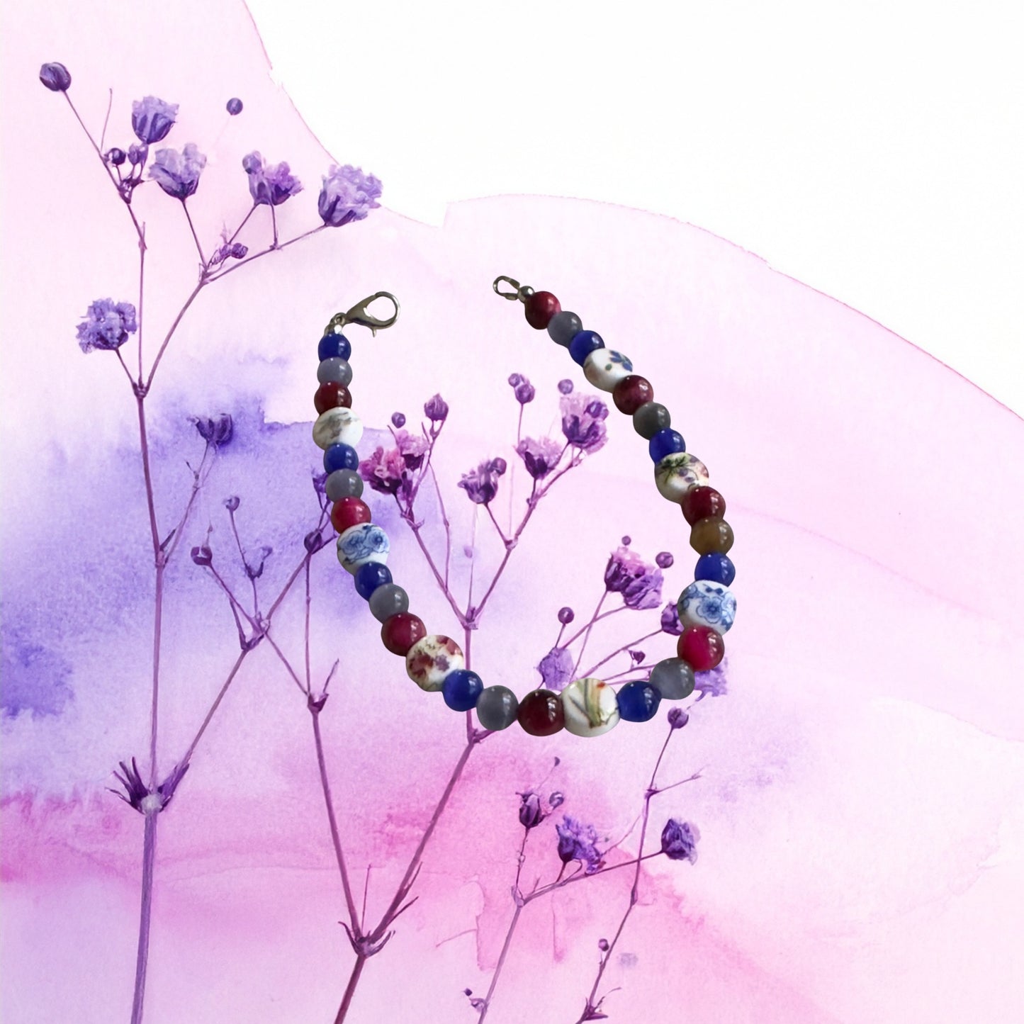     Artistic bracelet flat lay with purple flowers and pastel pink background inspired by bisexual Pride colors.