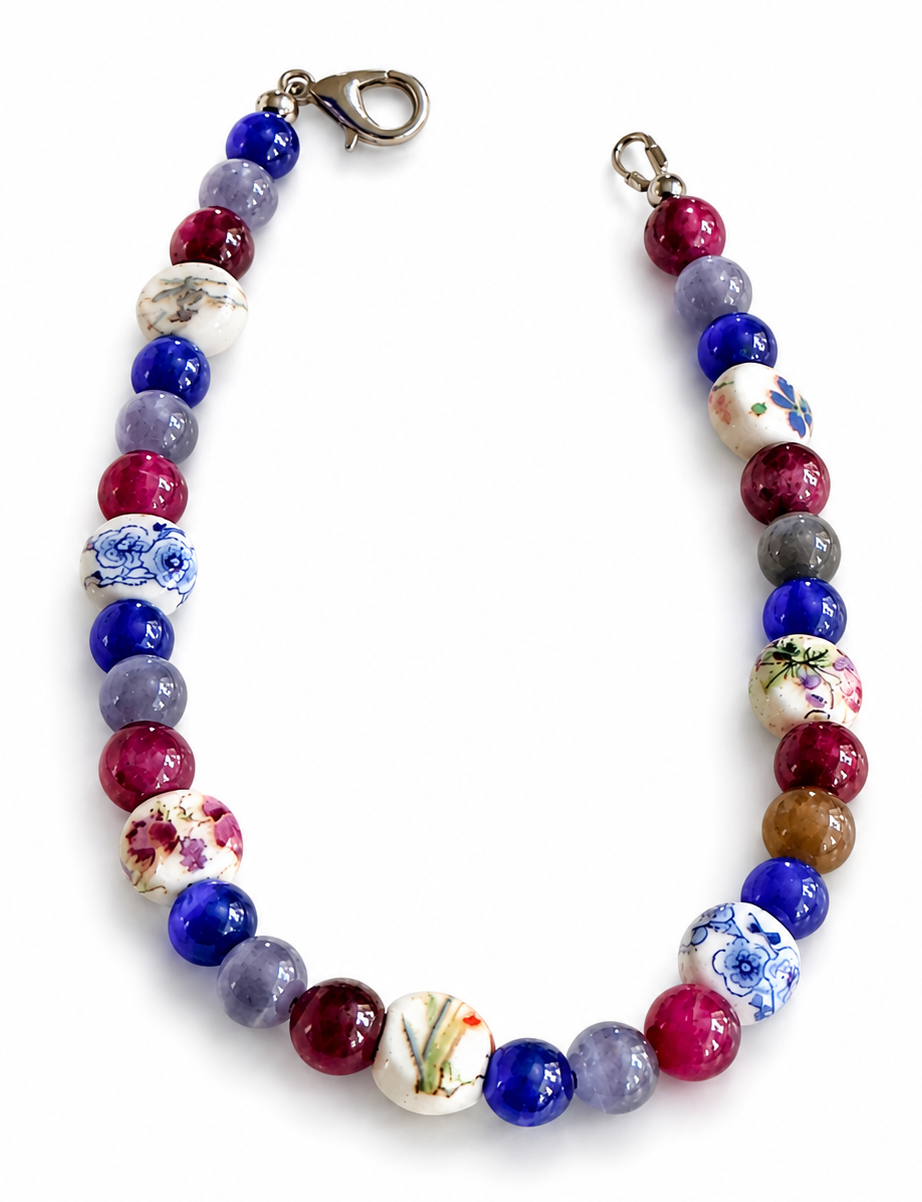  Handmade bisexual Pride bracelet with porcelain floral beads, blue gemstone beads, and pink accents on a clean white background.