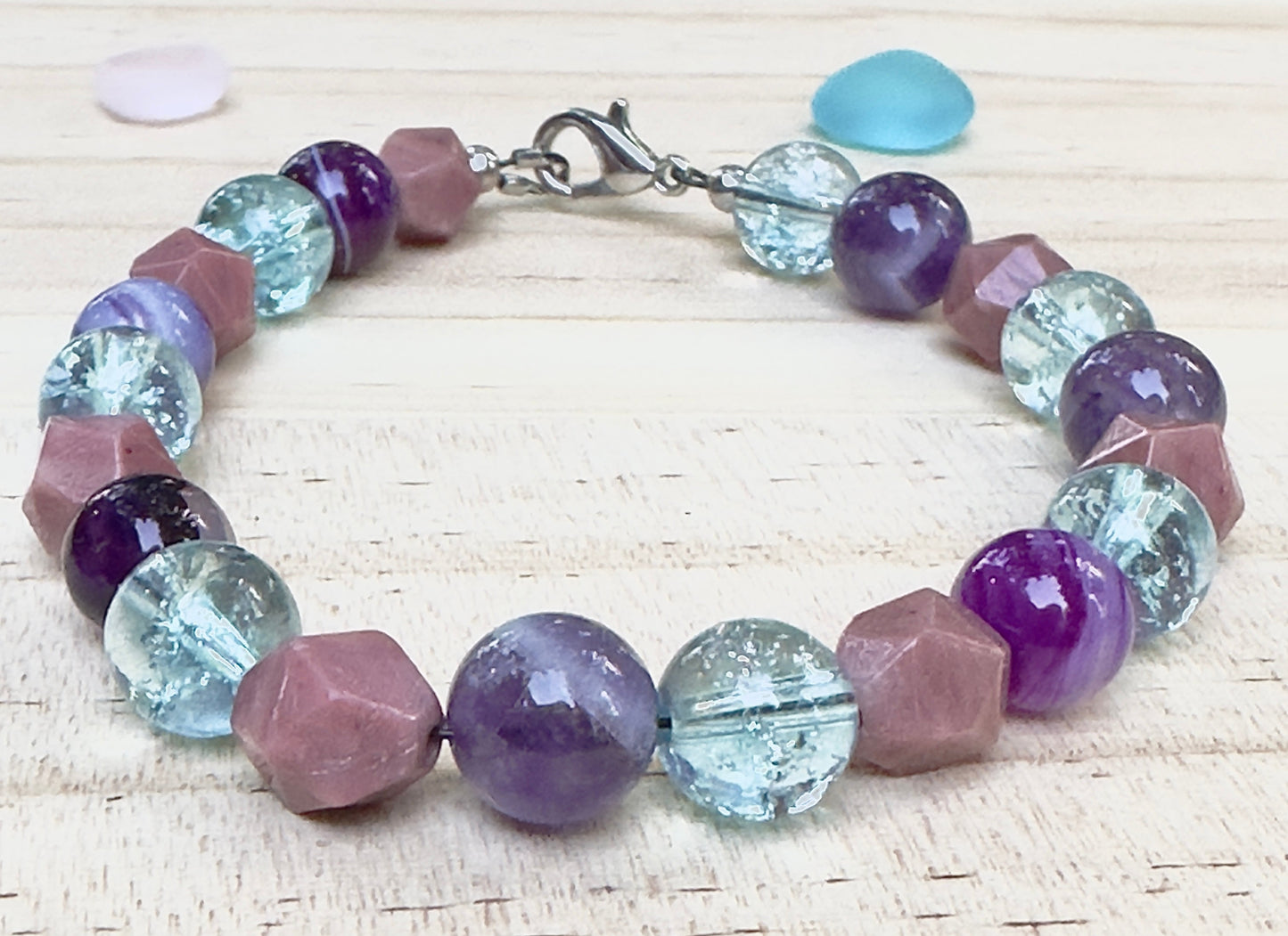 Close up angled view of handmade purple aqua and mauve gemstone bracelet